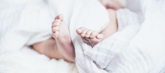 Adorable baby feet in white blanket.