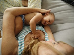 Here's an alt tag for the image: Happy baby playing with mother on couch.