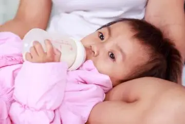 Baby girl drinking milk from bottle.
