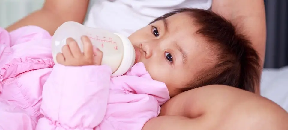 Baby girl drinking milk from bottle.