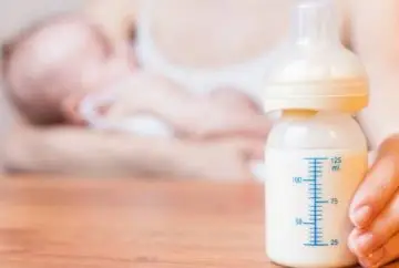 Baby bottle with formula, infant sleeping.