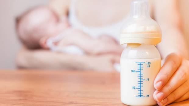 Baby bottle with formula, infant sleeping.