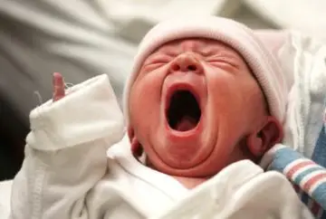 Newborn baby crying loudly in hospital.