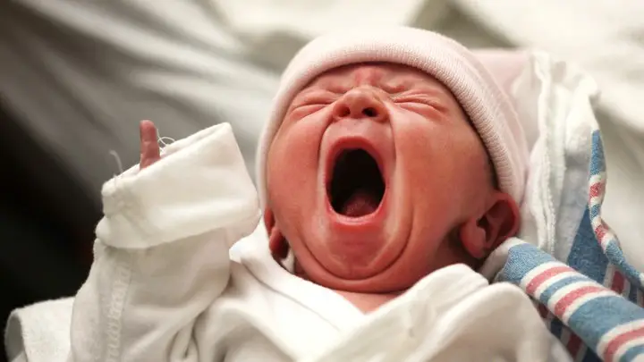 Newborn baby crying loudly in hospital.