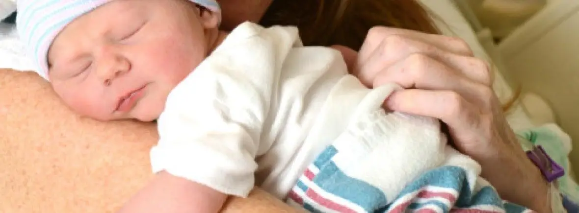 Newborn baby sleeping on mother's shoulder.