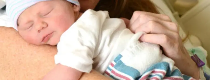 Newborn baby sleeping on mother's shoulder.