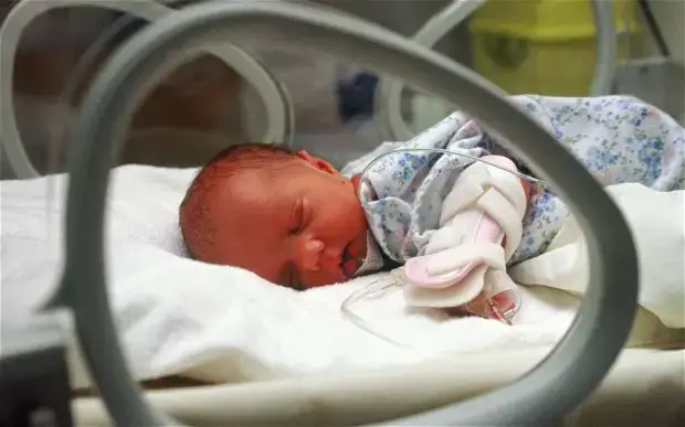 Premature baby sleeping in incubator.