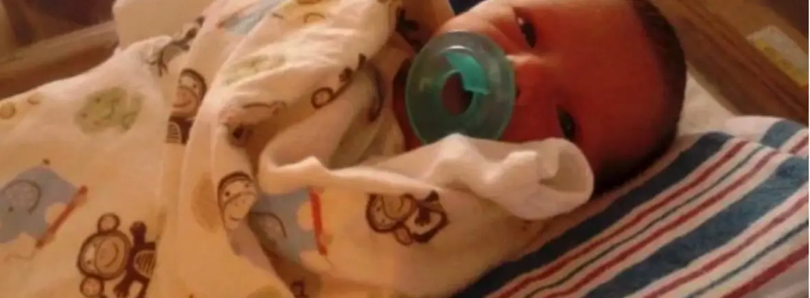 Newborn baby in swaddling blanket.