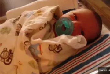 Newborn baby in swaddling blanket.