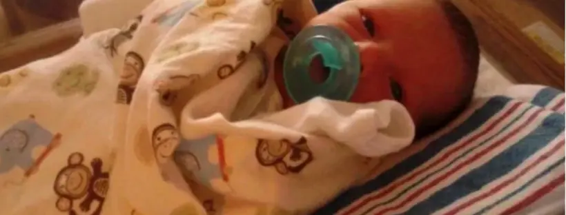 Newborn baby in swaddling blanket.