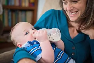 Woman feeding baby from bottle.