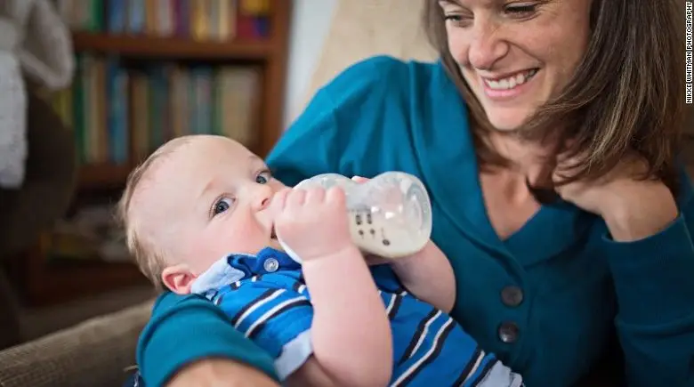 Woman feeding baby from bottle.