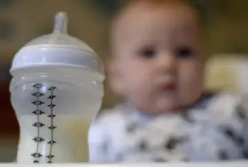 Baby bottle with milk, blurred baby.