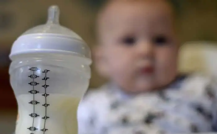 Baby bottle with milk, blurred baby.