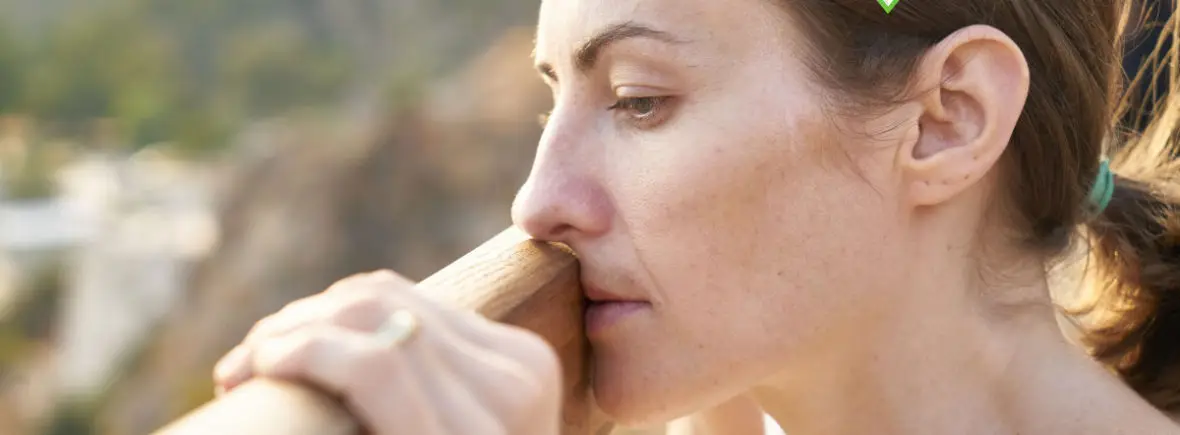 Woman pensively holding wooden railing.