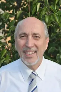 Here's an alt tag for the image: Smiling man in white shirt and tie.