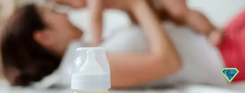 Baby bottle, mom and baby in background.