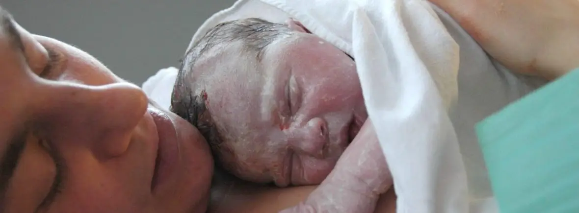 Newborn baby resting on mother's chest.