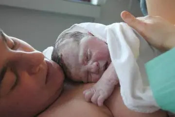 Newborn baby resting on mother's chest.