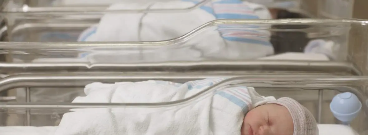 Newborn baby sleeping in hospital bassinet.
