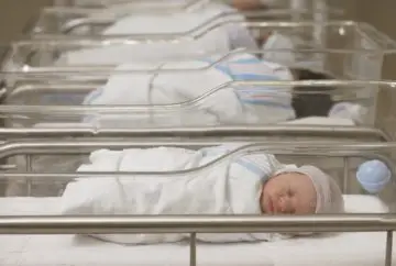 Newborn baby sleeping in hospital bassinet.