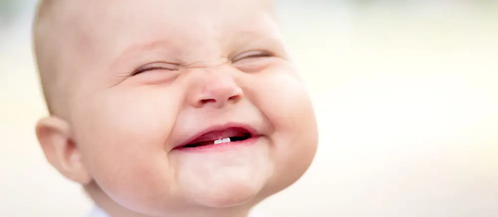 Smiling baby with first teeth.