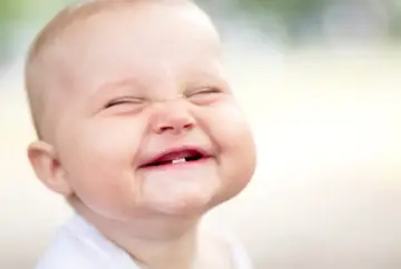 Smiling baby with first teeth.