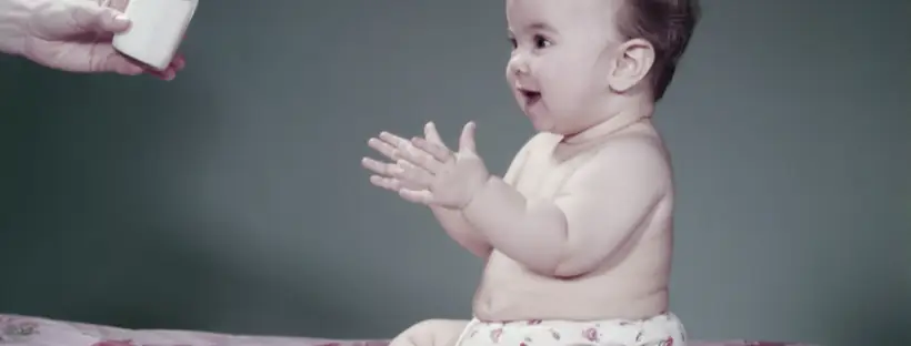Baby eagerly anticipates milk bottle.